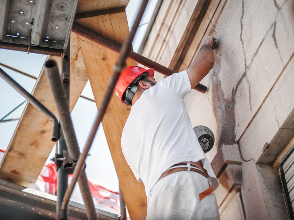 Man worker standing on scaffolding, perform work on the restoration of the facade of the old building. Repairing and renovate